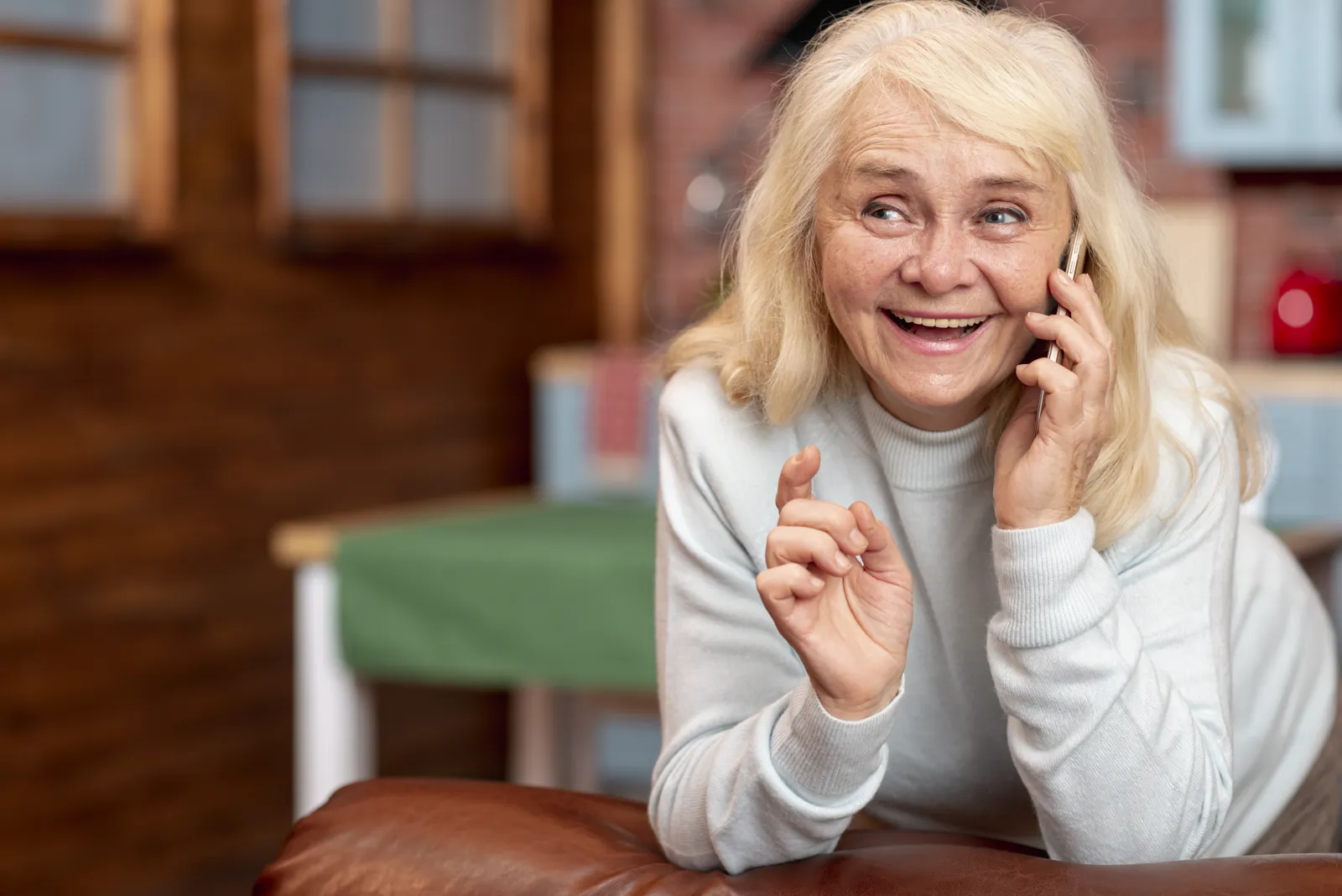Lächelnde Seniorin nimmt telefonisch Kontakt zur Pflegeberatung auf