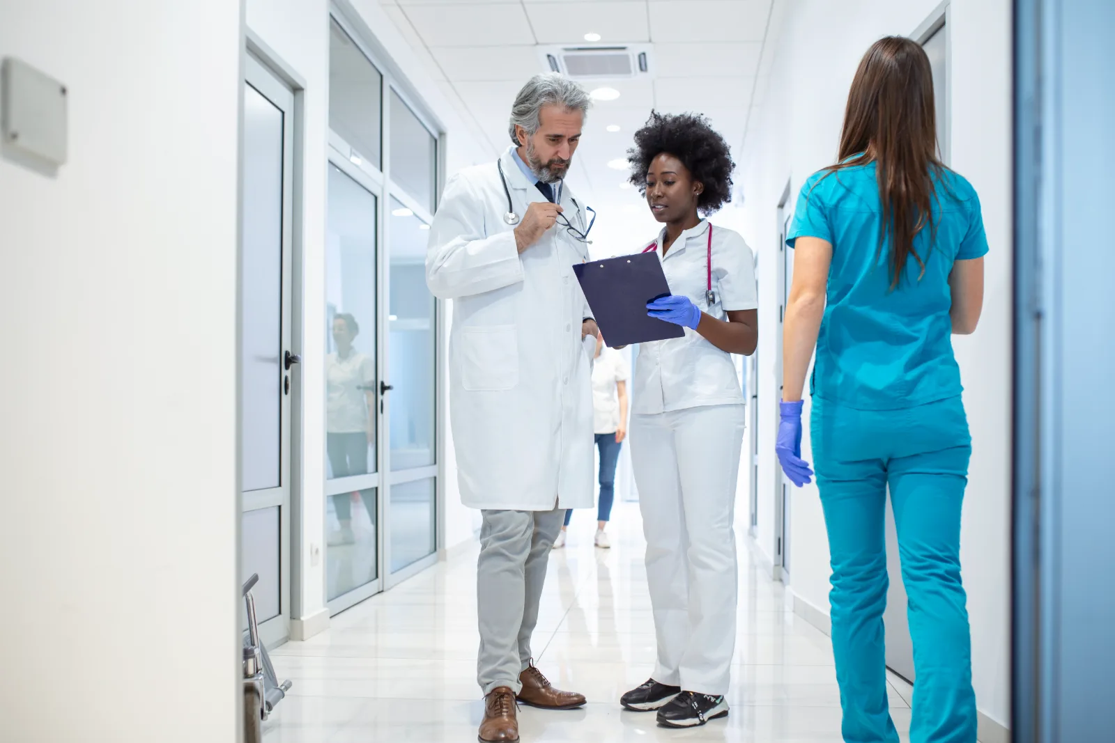 Pflegekraft und Arzt besprechen im Klinikflur gemeinsam einen Bericht